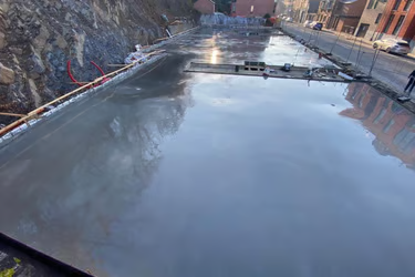 Coffrage, ferraillage et coulage d'une grande dalle de béton lissée.