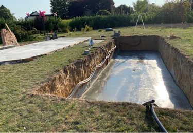 Chantier de piscine enterrée en cours de terrassement dans un jardin