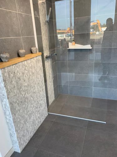 Carrelage grand format, mur en pierre et paroi vitrée sur mesure.